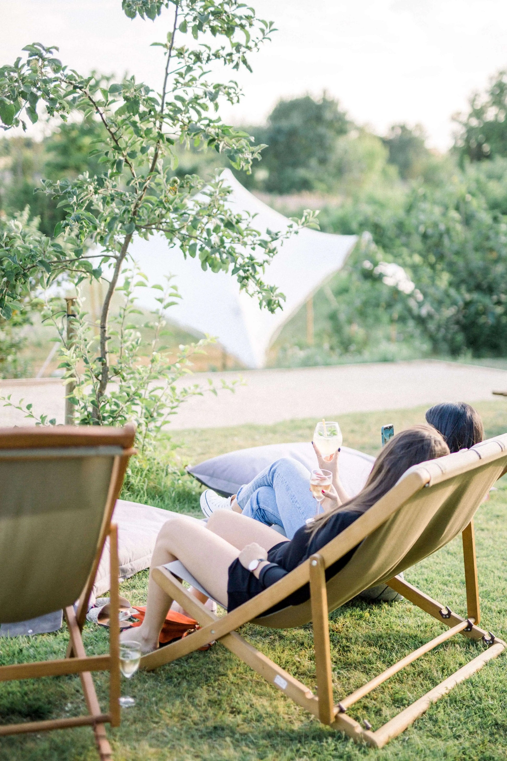 Repos en extérieur devant le terrain pétanque de Terre Ugo. Les clients boivent un verre de vin. 
