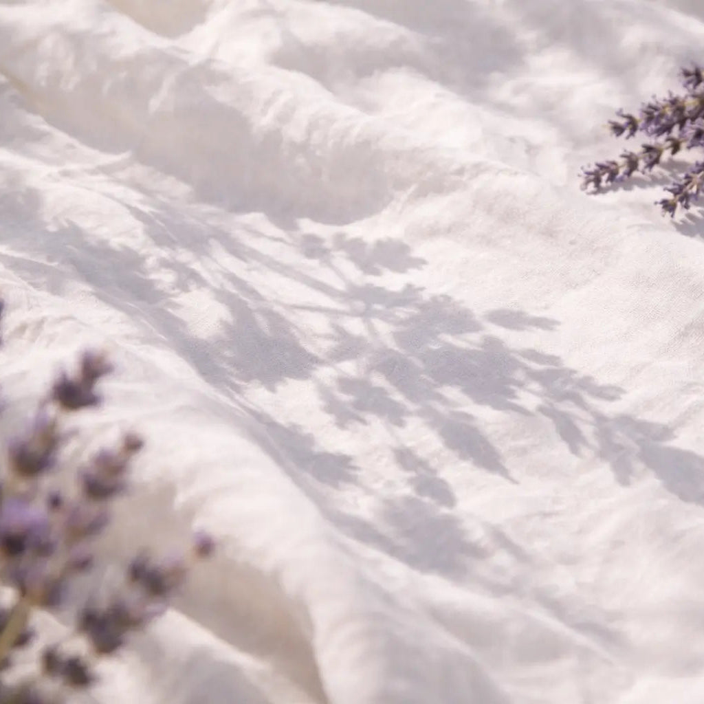 L'ombre des lavandes contre un tissu de lin blanc.